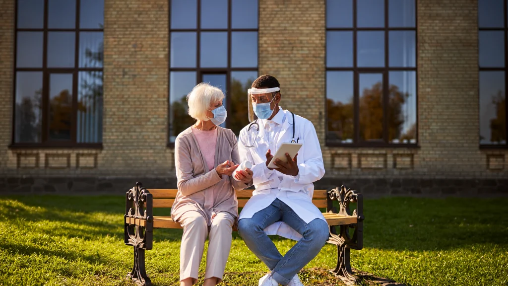Elderly couple sitting on a bench outside a rural clinic